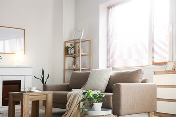 Naklejka premium Interior of light living room with grey sofa, table and window