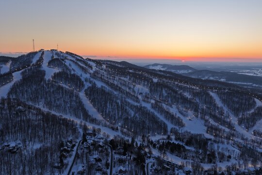 Aerial drone view of illuminated Bromont ski resort slopes at dusk, Quebec, Canada in winter. g.