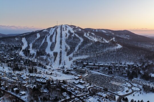 Aerial drone view of illuminated Bromont ski resort slopes at dusk, Quebec, Canada in winter. g.