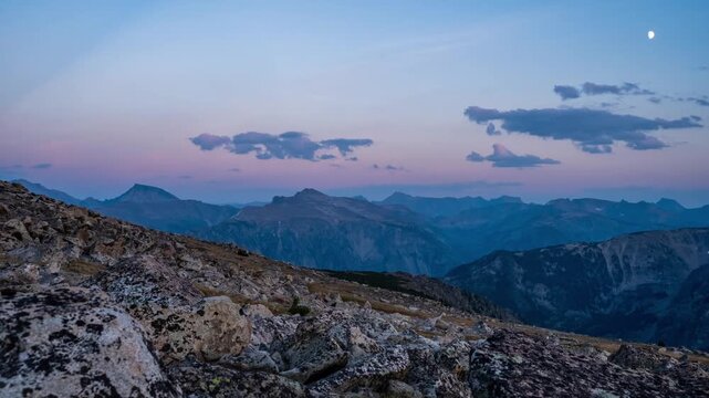 Pink sunset clouds drifting over rugged peaks and rocky slopes as the moon appears, Beartooth high country, Montana, time lapse