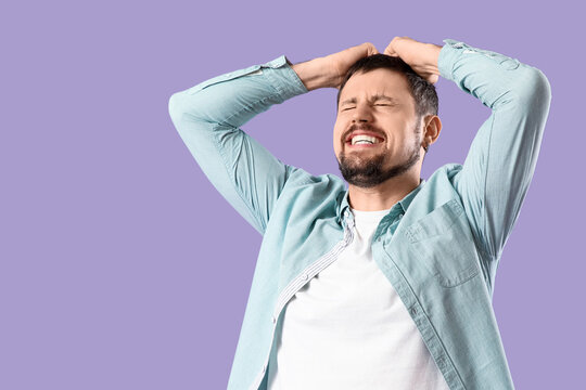 Screaming young man on lilac background