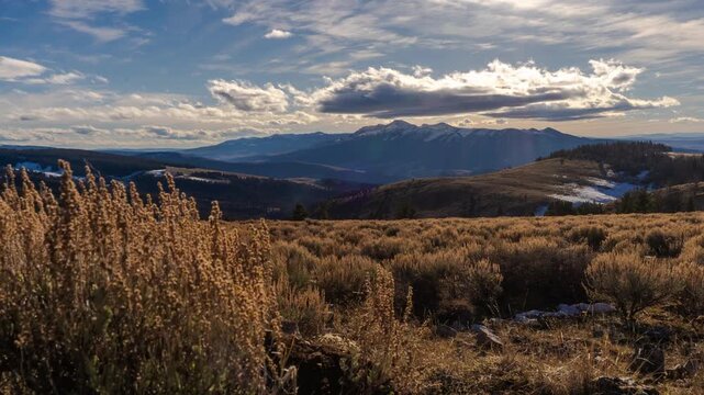 Clouds drifting over the Snowcrest Range beyond golden sagebrush in late autumn light, Gravelly Range, Montana, time lapse