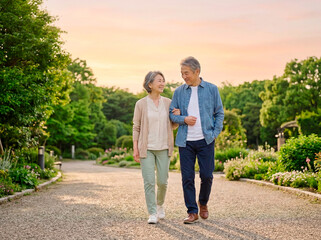 Obraz premium 夕暮れの公園を歩くシニア夫婦