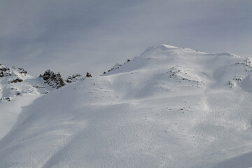 Snow covered mountain slope with ski tracks crisscrossing the surface