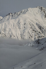 Snow covered mountain range with clouds partially obscuring its base