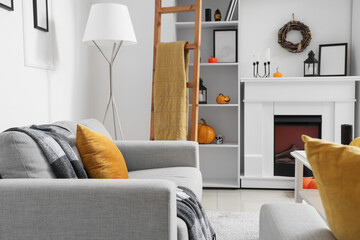 Naklejka premium Interior of light living room decorated for Halloween with sofa, fireplace and shelf unit