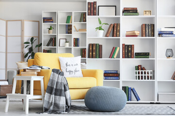 Interior of stylish living room with yellow armchair, pouf and bookshelf © Pixel-Shot