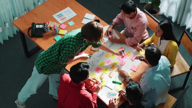 Close up of professional business team hands writing and putting sticky note on scrum task board. Top view of project manager write task and use kanban board to manage time and workflow. Convocation.