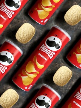 Top view on red original Pringles Chips can pattern with slice of Pringles Chips potatoes on black concrete background. Perfect vertical ads promo banner for Pringles Chips 