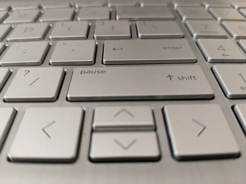 Silver laptop keyboard with focus on arrow and shift keys
