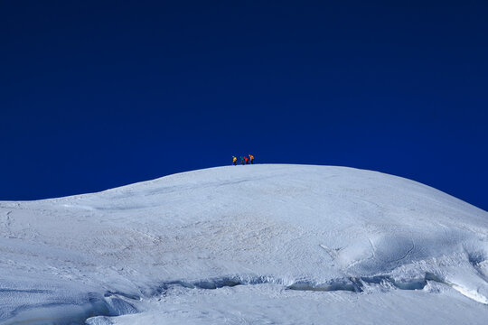 Mountaineers in rope team with crampons descending from summit Parrotspitze on mountain massif Monte Rosa with glacier in summer in Pennine Alps, Italy