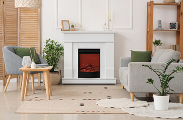 Naklejka premium Fireplace, sofa and houseplants in interior of light living room