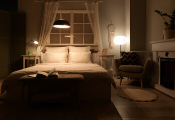 Naklejka premium Interior of dark bedroom with armchair, fireplace and glowing lamps