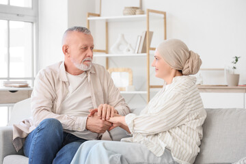 Obraz premium Mature woman after chemotherapy with her husband holding hands on sofa at home