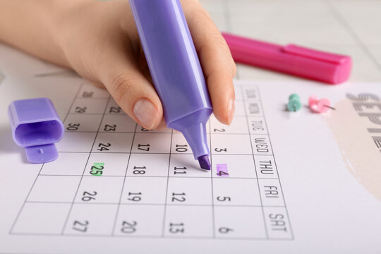 Female hand marking dates with markers in calendar, closeup. Planning concept