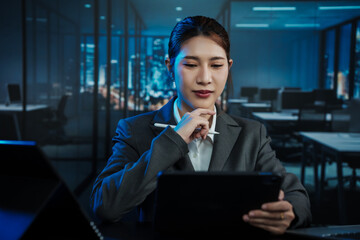 Focused businesswoman using tablet in modern office at night