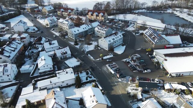 Bavarian village in southern Germany during winter with snow covered rooftops and small town streets. Drone aerial view over rural landscape and quiet residential neighborhood in Bavaria.