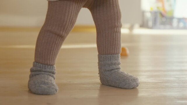 Baby's first steps on wooden floor. Perfect for family or parenting projects.