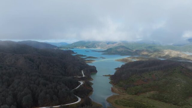 Aerial pullback of rainbow over Aoos Springs Lake Techniti Limni Aoou in Epirus Greece with low hanging clouds