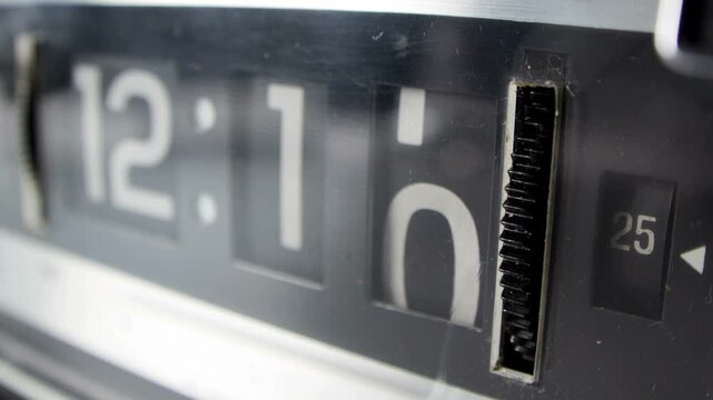 Time-lapse footage of a vintage flip clock showing the time as mechanical flaps rotate to display hours and minutes. The close-up highlights the retro design, glossy numbers, and visible mechanism.