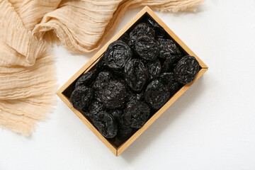 Obraz premium Wooden box with dried prunes on white background