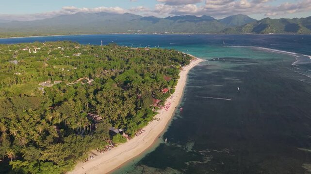 Orbiting aerial view of Gili Air beach, turquoise sea, and Lombok mountains in Indonesia