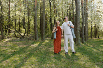 Fototapeta premium Couple enjoying a sunny day in the forest, wearing stylish summer outfits and sunglasses