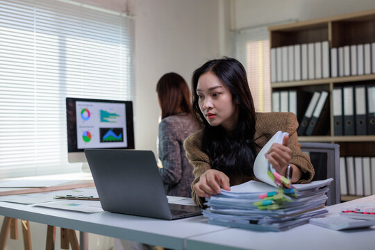 Young businesswoman managing document workload in office