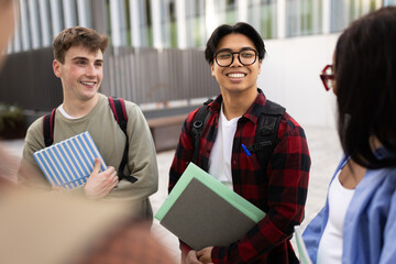 Happy multi-ethnic students chatting together between classes on campus
