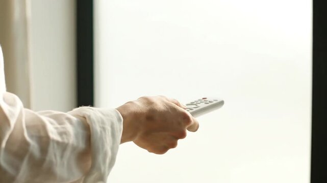 Person Using Remote Control Near Window.