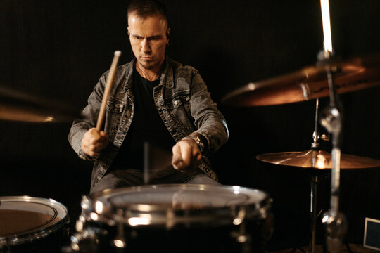 Focused drummer rehearsing in studio with drum set.