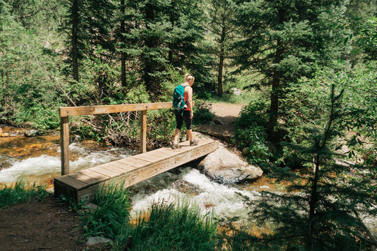 Woman hiker crossing over Deer Creek on footbridge