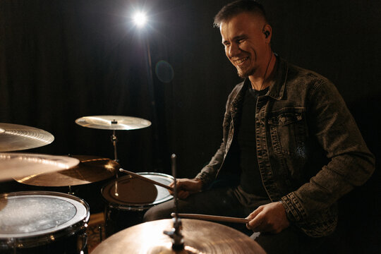 Smiling drummer playing drums at rehearsal.