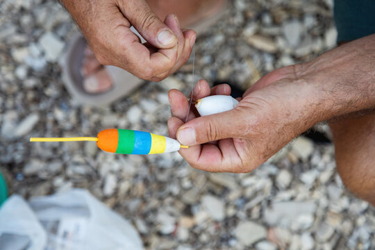 Man's hands attaching fishing float to line closeup