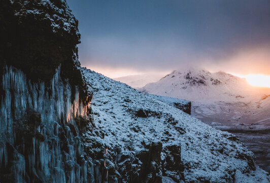 Setting winter sun in Iceland hits large icicles on mountainside.