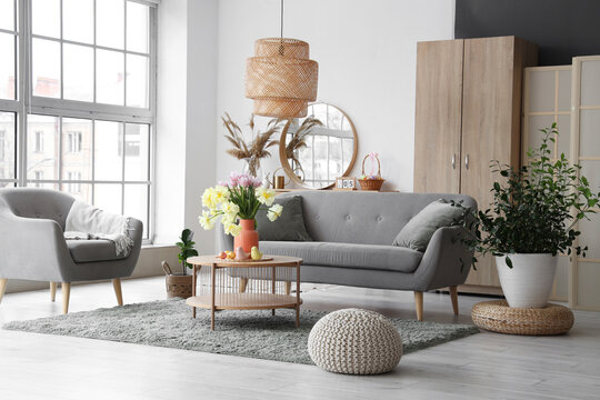 Interior of modern living room with flowers, Easter eggs and porcelain quails on coffee table