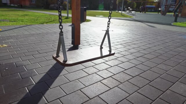 Swing set at park casts long shadows in afternoon light during playtime