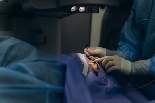 Surgeon performing eye operation on patient in blue surgical gown