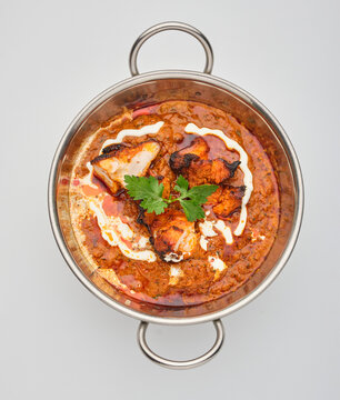 Chicken curry served in a silver bowl with rice on a white table during lunchtime in a restaurant