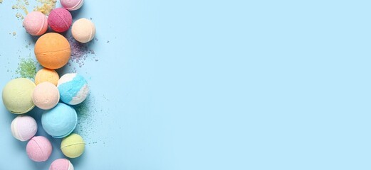Many different bath bombs and sea salt on light blue background with space for text, top view
