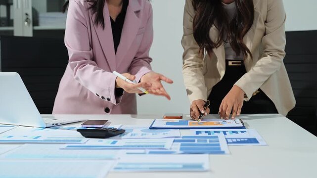 Business documents on office table with smart phone and calculator digital tablet and graph business with social network diagram and two colleagues discussing data working in the office.