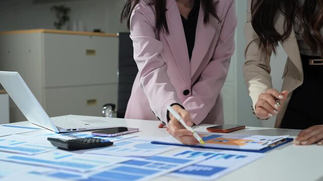 Business documents on office table with smart phone and calculator digital tablet and graph business with social network diagram and two colleagues discussing data working in the office.