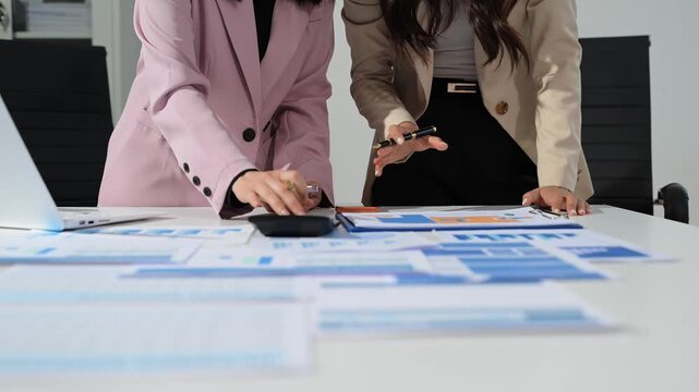 Business documents on office table with smart phone and calculator digital tablet and graph business with social network diagram and two colleagues discussing data working in the office.