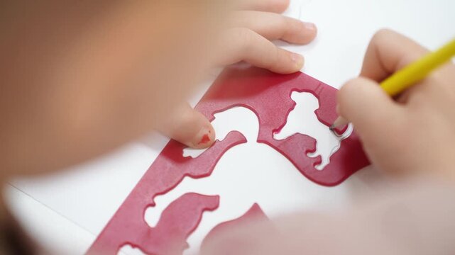 A girl on a stencil circles animals with a pencil. Kindergarten classes. Close-up. High quality video