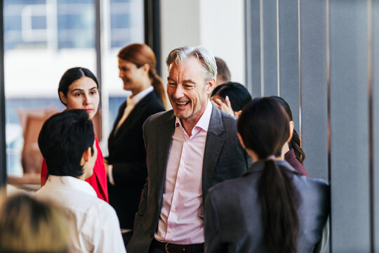 Professionals networking and chatting in a bright office corridor during a business event.
