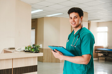 Smiling healthcare professional in green scrubs with a stethoscope holding a clipboard at a...