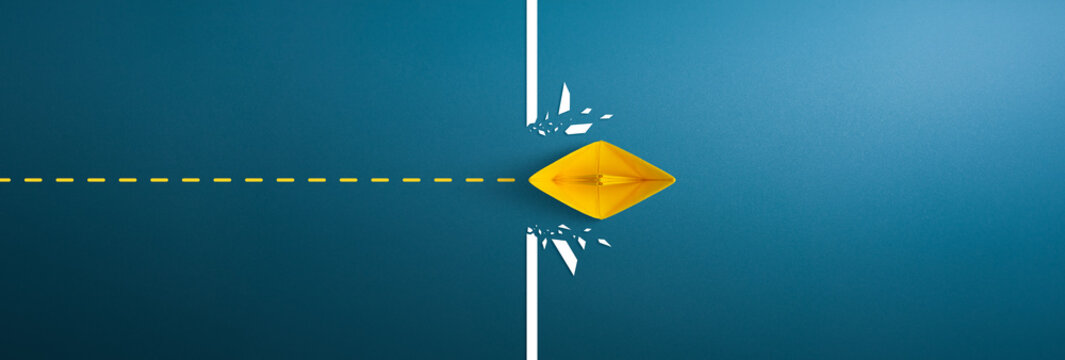Yellow paper ship breaking through obstacle on blue background, Concept of overcoming barriers, goal, target