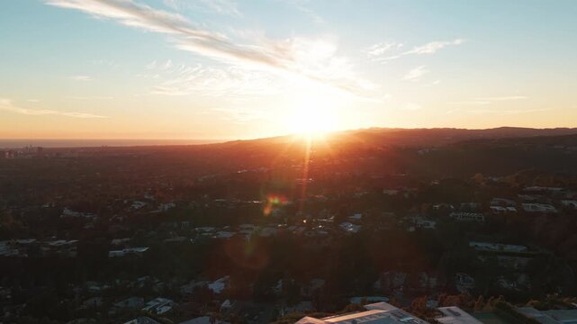 Aerial rising and panning shot of the sun setting over Beverly Hills, California. 4K