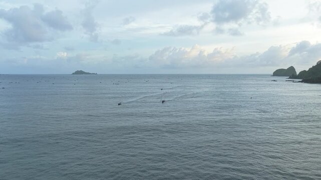 Aerial view of traditional indonesian fishing boats sailing across the open ocean near red island, java, with a distant island on the horizon