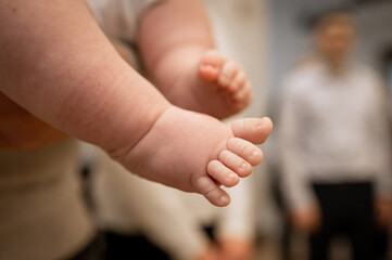 Close up of cute chubby newborn baby feet on blurred background of people